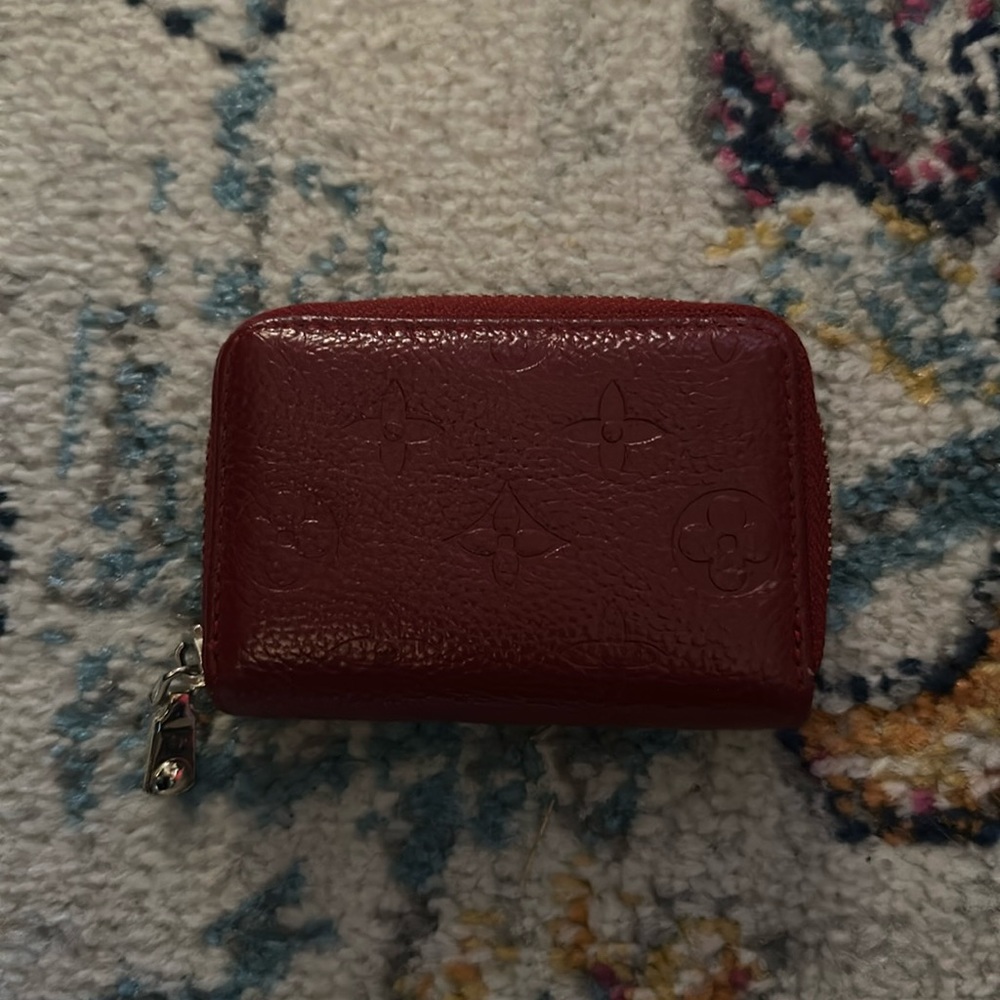 Deep red embossed with imprint detailing accordion zip around wallet